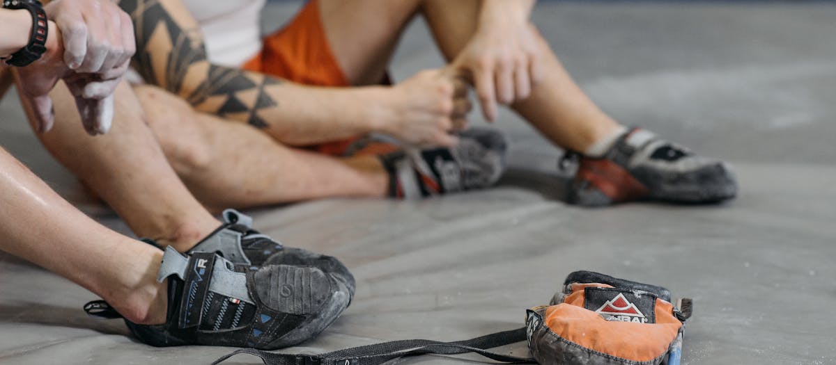 Close-up of climbers seated on gym floor with climbing gear.