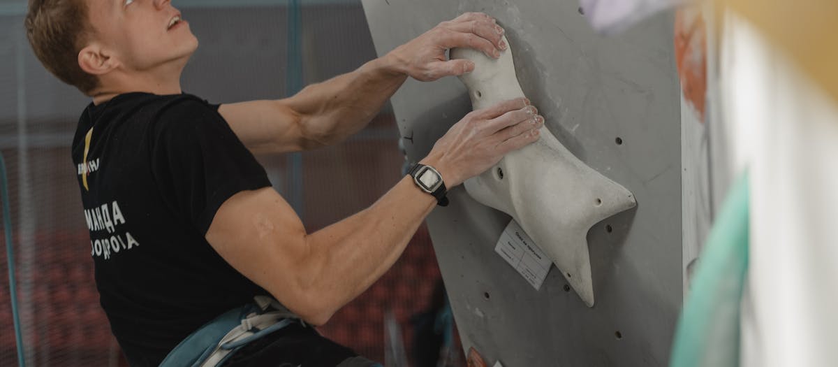 Male climber on an indoor climbing wall demonstrating focus and determination.